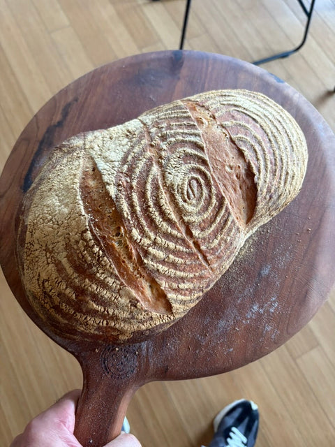 Artisan bread with banneton ring pattern on a wooden peel — open baked on a Baking Steel