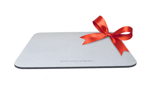 Baking Steel Original with a simple ribbon tied around it, photographed on a clean white background as a modern, minimalist gift for home cooks.