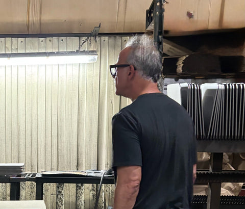 Andris Lagsdin, founder of Baking Steel, inside Stoughton Steel fabrication plant in Hanover, MA with finished Baking Steels stacked in the background.