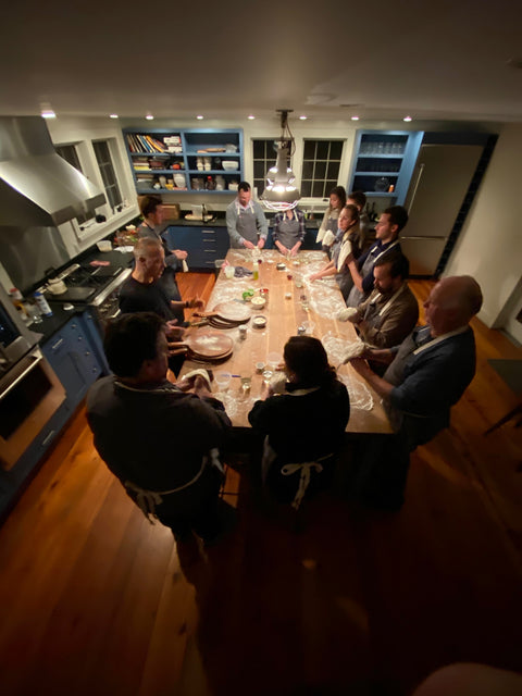 Pizza making class at Andris Lagsdin's Cohasset cooking studio, guests gathered around a flour-covered kitchen island learning to make pizza on a Baking Steel