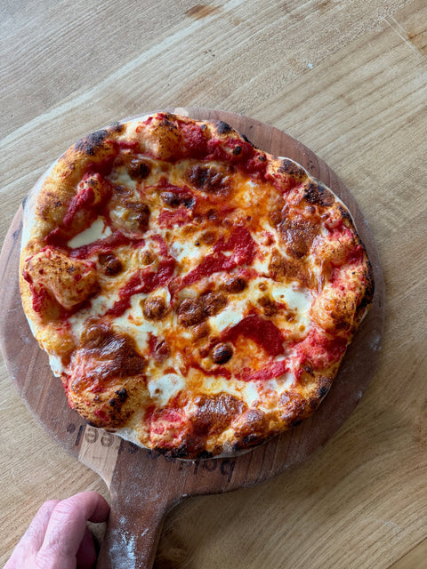 Homemade cheese pizza baked on a Baking Steel with crispy char crust, bubbling mozzarella and San Marzano tomatoes on a wooden pizza peel