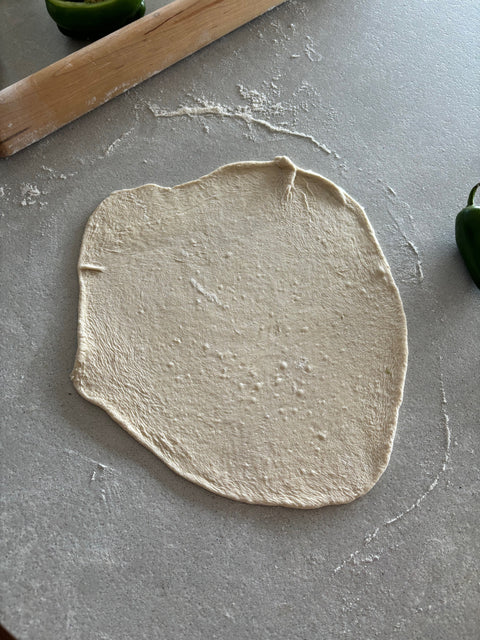 thin crust dough rolled out thin on a counter top 
