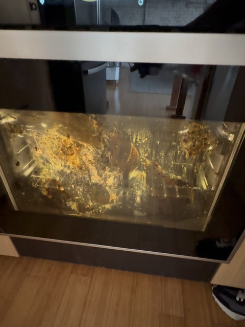 Dirty oven glass about to be scoured with a Baking Steel Cleaning Brick.