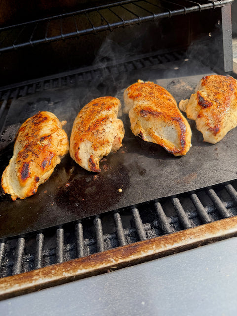 Four chicken breasts cooking on a Baking Steel on the Grill.