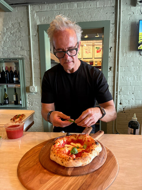 Andris Lagsdin topping a Margherita pizza with fresh basil at Pauly's Wine Experience in Grand Rapids, Michigan