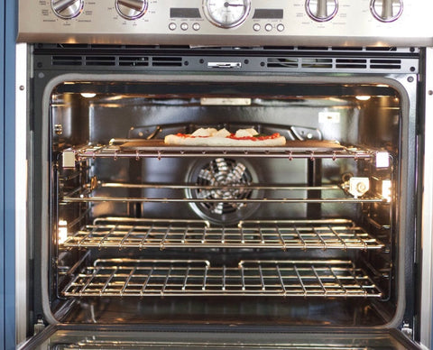 Baking Steel inside an electric wall oven on the top rack with a pizza on top, ready to bake.