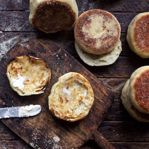 Freshly made English muffins showing perfect nooks and crannies texture, cooked on griddle with golden-brown crust and semolina flour coating